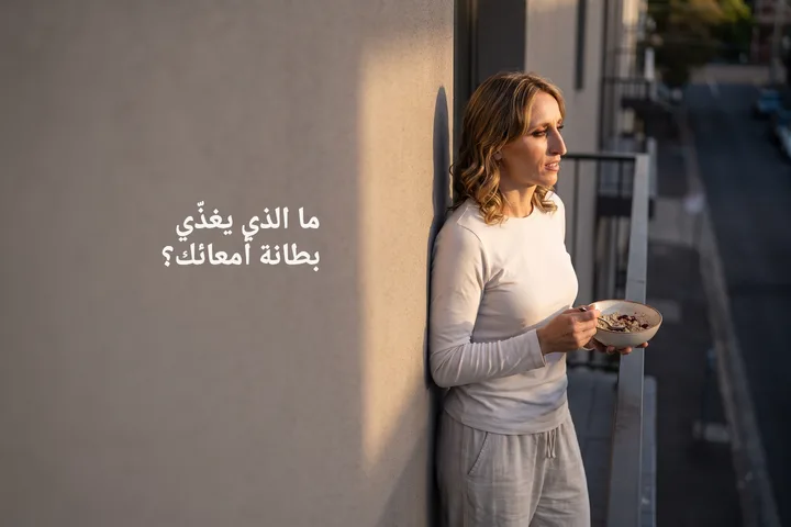ما الذي يغذّي بطانة أمعائك؟ — شابة في العشرينيات تأكل صحن شوفان في شرفتها تحت آخر ضوء الشمس