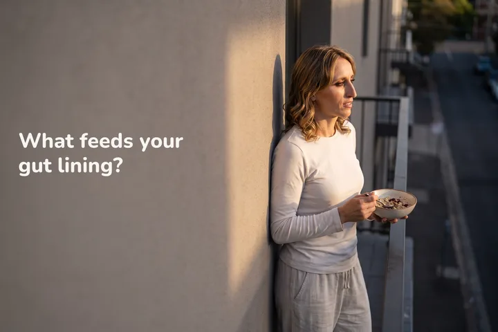 What feeds your gut lining? — a woman in her twenties eats a bowl of oats on her balcony in the last sun