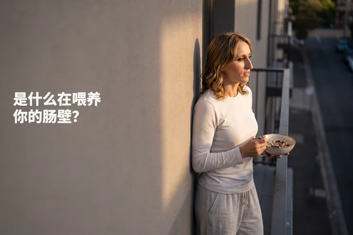 是什么在喂养你的肠壁? — 一位二十多岁的女性在阳台上就着最后一点阳光吃一碗燕麦