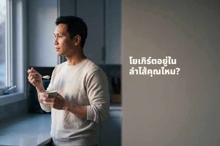 โยเกิร์ตอยู่ในลำไส้คุณไหม? — ผู้ชายคนหนึ่งกินโยเกิร์ตรสธรรมชาติที่เคาน์เตอร์ครัวในแสงแรกของวัน