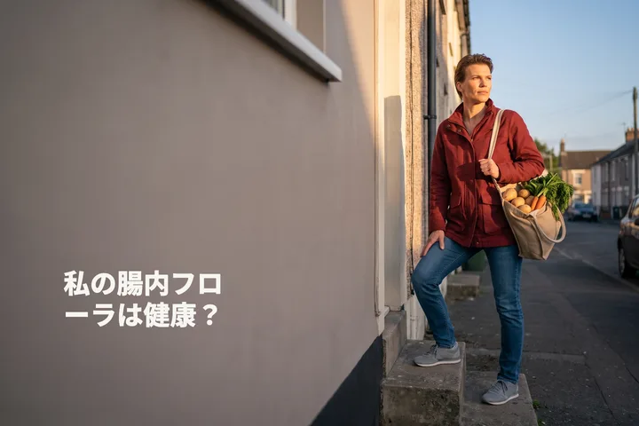 私の腸内フローラは健康? — 夕暮れ、野菜の袋を提げた女性が自宅の玄関階段を上がる