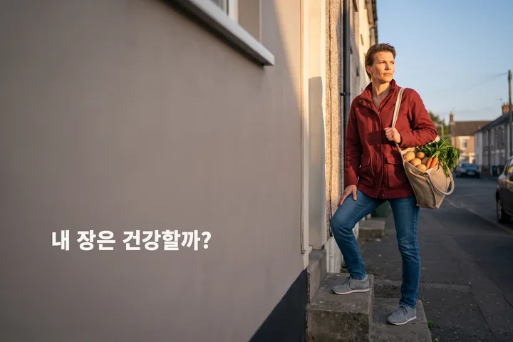내 장은 건강할까? — 저녁 무렵 채소 봉지를 든 여성이 자기 집 현관 계단을 오른다