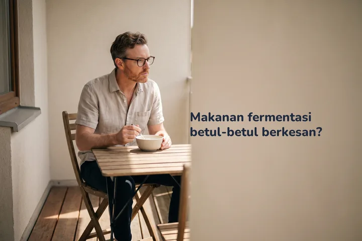 Makanan fermentasi betul-betul berkesan? — seorang lelaki makan semangkuk kefir di meja kecil di balkoninya